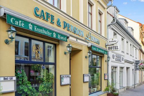 a yellow building with signs on it on a street at Hotel-Pension Lender in Bad Freienwalde