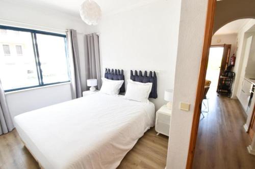 a white bed in a room with a large window at Beach House Quiaios in Figueira da Foz