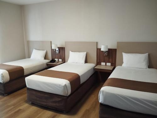 a hotel room with two beds and two lamps at DM Hoteles Ayacucho in Ayacucho