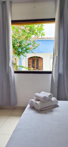 a bed with two towels on it in front of a window at Aloogar Caragua Beach in Caraguatatuba