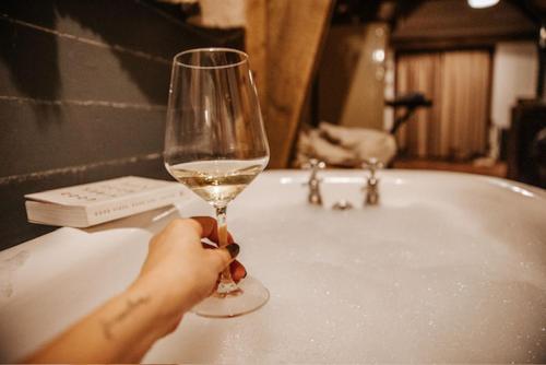 a person holding a glass of wine in front of a sink at Sky Cabin. Cosy Forest Log Cabin 3 night minimum in Wareham