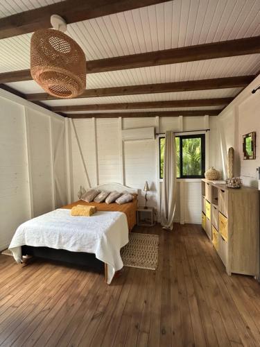 a bedroom with a bed and a wooden floor at Bungalow cocon des alizés in Les Abymes