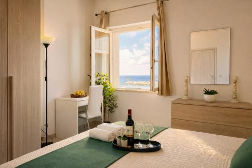 a room with a table with wine glasses and a window at Demetra Seafront Apartment - Parking & Pool in Castel Volturno