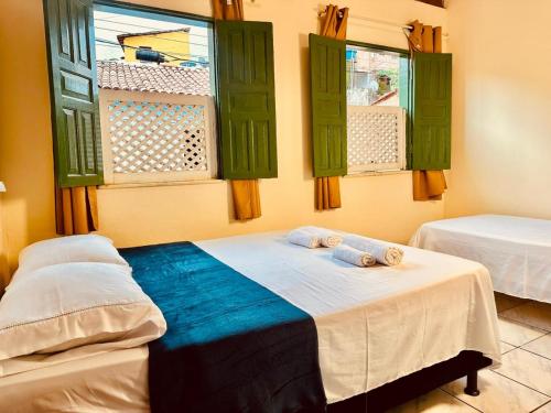 a room with two beds and green windows at Casa de Nara in Lençóis