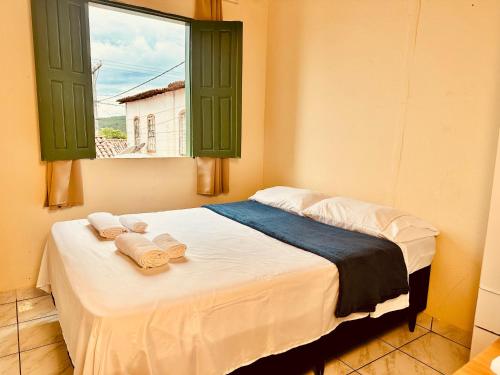 a bedroom with a bed with towels and a window at Casa de Nara in Lençóis