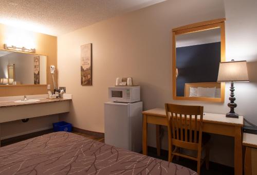 a hotel room with a bed and a desk and a microwave at EasyStay Inn & Suites Fernie in Fernie