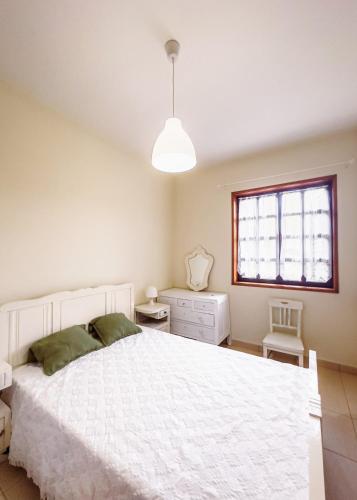 a bedroom with a white bed and a window at Barbeito Country House in Paraíso