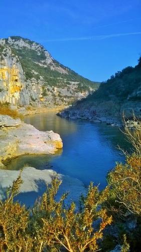 a river with rocks in the middle of a mountain at La chambre secrète in Aiguèze
