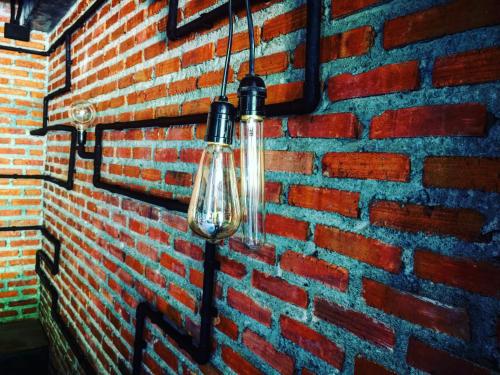 a glass light bulb hanging on a brick wall at Keeree Loft Resort คีรีลอฟท์รีสอร์ท in Thong Pha Phum