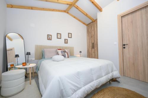 a bedroom with a white bed and a wooden door at La casa di Antonio Corfu in Alepou