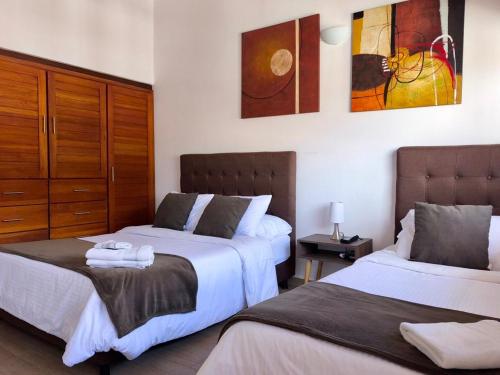 a bedroom with two beds and a painting on the wall at Casa ONCE ONCE in Villa de Leyva