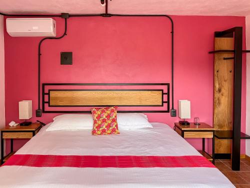 a bedroom with a large bed with a pink wall at Suites Patio Antequera in Oaxaca City
