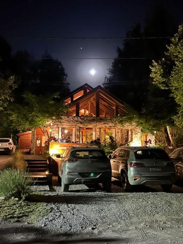 two cars parked in front of a house at night at Hostería Brisas del Cerro in Villa La Angostura