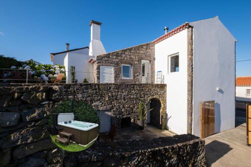 a house with a stone wall and a sink at Casa do Simão, Açores - Now with hot tub! in Nordeste