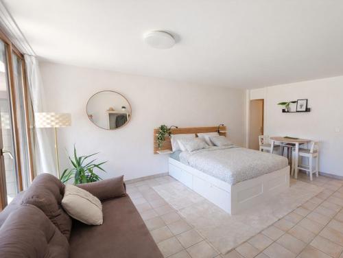 a bedroom with a bed and a table and a couch at Bright studio Martigny - 30 min from Verbier - free parking in Martigny-Ville