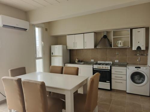 a kitchen with a white table and chairs and a stove at Depto tranquilo y equipado cerca del mar in Puerto Madryn