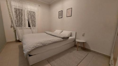 a small white bedroom with a bed and a window at Christina Apartment 2 in Drama