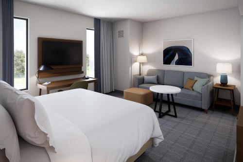 a hotel room with a bed and a couch and a television at Staybridge Suites Pensacola Airport by IHG in Pensacola