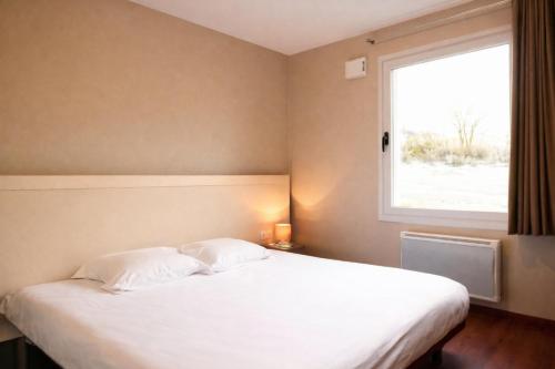 a bedroom with a white bed with a window at Les Balcons du Sancy - Résidence de Tourisme in Picherande