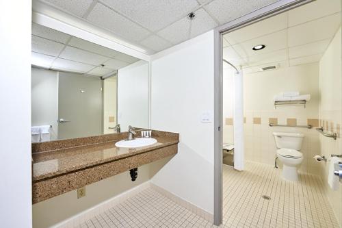 a bathroom with a toilet and a sink and a mirror at Canad Inns Destination Centre Fort Garry in Winnipeg