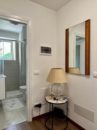 a bathroom with a table with a lamp and a mirror at Casa Verde Valsassina 2 in Primaluna