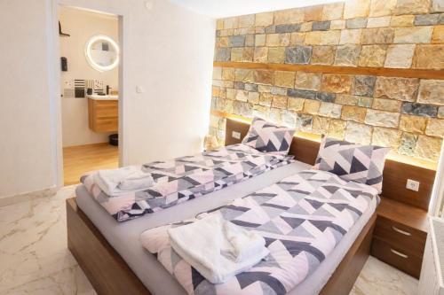 a bedroom with a bed with a stone wall at Къща за гости Брязово in Ribarica