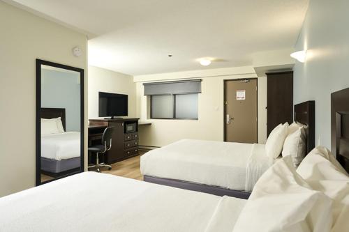 a hotel room with two beds and a mirror at Canad Inns Destination Centre Fort Garry in Winnipeg