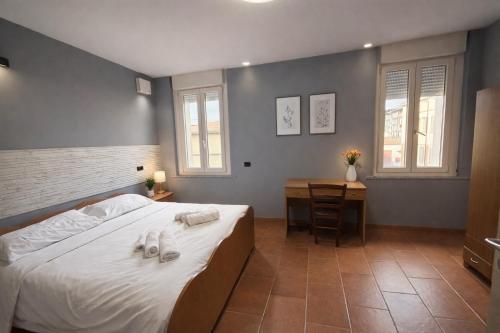 a bedroom with a bed and a desk and windows at Palazzo Gregorio in Parma