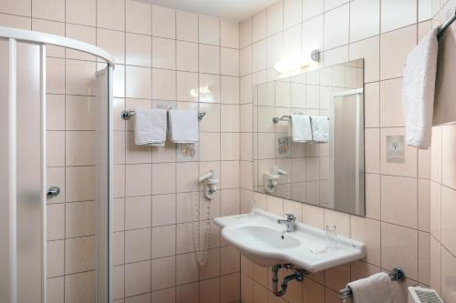 a bathroom with a sink and a shower with a mirror at B&B Number 1 in Loipersdorf bei Fürstenfeld