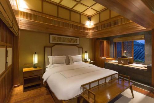 a bedroom with a large white bed and a table at 见天会馆 in Lijiang