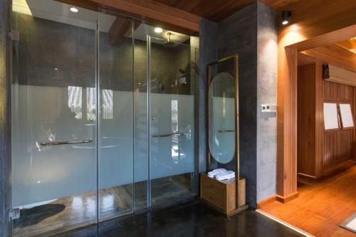 a bathroom with a glass shower with a mirror at 见天会馆 in Lijiang