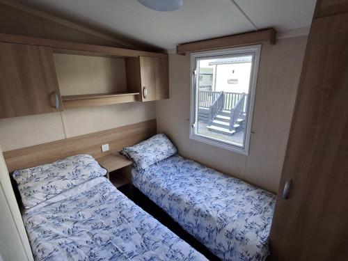 a small room with two beds and a window at Glasyln 37 in Porthmadog
