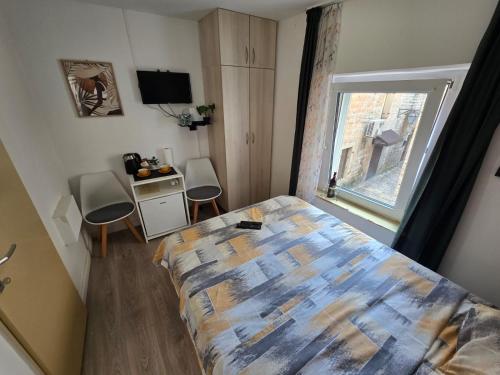 a bedroom with a bed and a desk and a window at Apartman Stari grad, Budva in Budva
