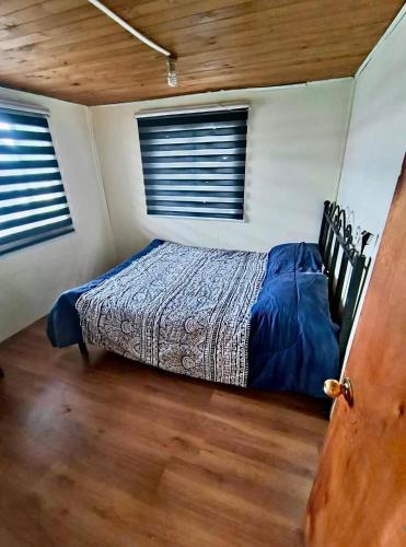 a bedroom with a bed in a room with two windows at Refugio PARQUE NACIONAL ALERCE ANDINO in Puerto Montt