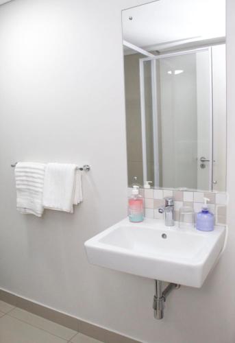 a white bathroom with a sink and a mirror at The Millennial, Secure parking, 3 mins to Gateway in Durban