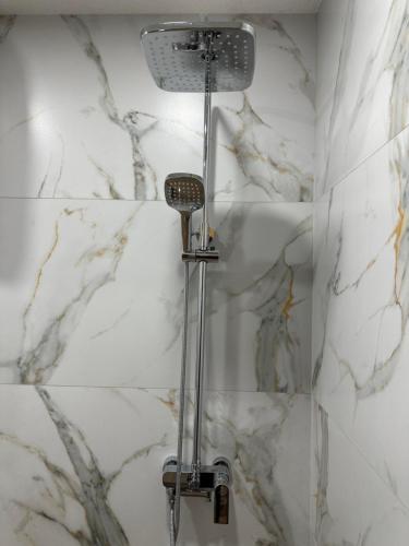 a shower in a bathroom with white marble walls at Martin's Apartment in Bansko
