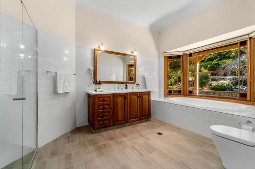 a bathroom with a tub and a sink and a mirror at Tiverton in Kurrajong