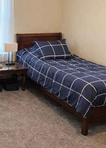 a bed with a blue and white comforter and a table at Colton Loop in Beckley