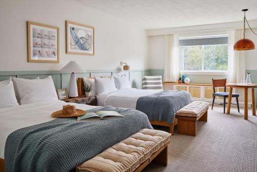 a hotel room with two beds and a bench with a book at Wayfinder Newport in Newport