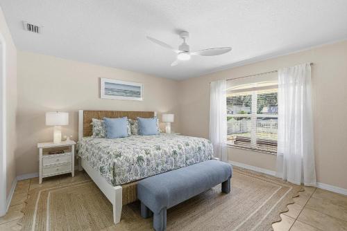 a bedroom with a bed with blue pillows and a window at Sip of Sun in New Smyrna Beach