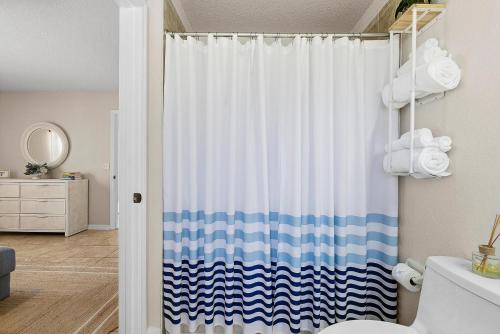 a bathroom with a shower with a blue and white shower curtain at Sip of Sun in New Smyrna Beach