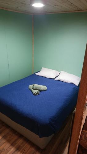 a bed with a blue bedsheet and a sweater on it at Cabaña monoambiente N 2 in Chaitén