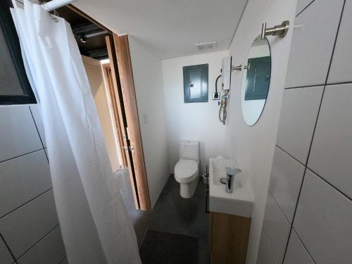 a small bathroom with a toilet and a mirror at Atom Cuatro 303 in Guatemala