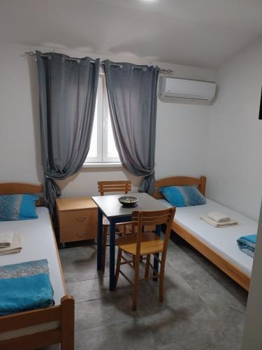 a room with two beds and a table and a window at LIBERO APARTMANI in Surčin