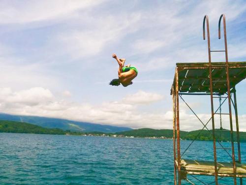 a man jumping off of a pier into the water at A short walk to Akakura Onsen Ski Lift and Town by Japow House in Myoko