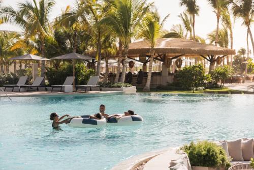 three people in a swimming pool at a resort at The St. Regis Cap Cana Resort in Punta Cana