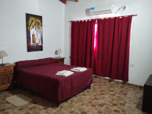 ein Schlafzimmer mit einem roten Bett und einem roten Vorhang in der Unterkunft HOTEL y EXCURSIONES TEJADA in Fiambala