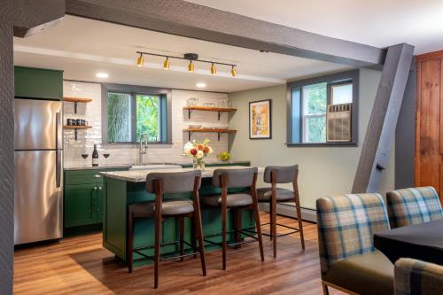a kitchen with green cabinets and a kitchen island with bar stools at La Tourelle Inn & Spa in Ithaca