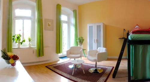 a room with two chairs and a bed and windows at Apartment Alaune in Dresden