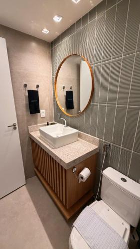 a bathroom with a sink and a mirror and a toilet at Novíssimo Flat Beach Class Solare - Muro Alto -Soft Open in Porto De Galinhas